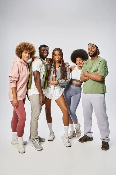 Alegres amigos afro-americanos em sportswear de pé juntos em pano de fundo cinza, Juneteenth — Fotografia de Stock