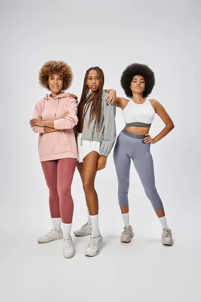Young african american women in sportswear standing together on grey backdrop, Juneteenth concept — Stock Photo