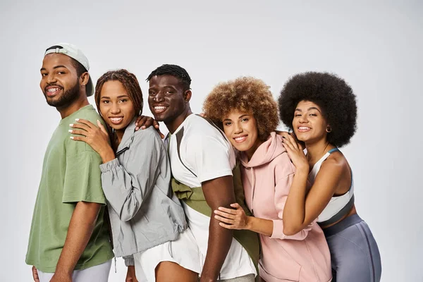 Grupo de jovens amigos afro-americanos positivos apoiando-se uns nos outros em fundo cinza, comunidade — Fotografia de Stock