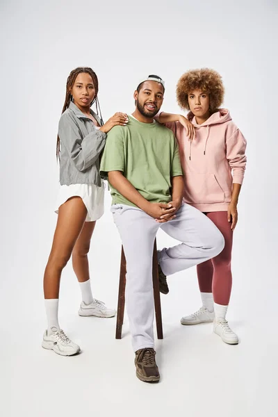 Young african american women standing near man and posing together on grey background, community — Stock Photo