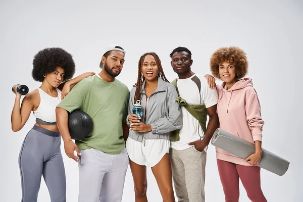 Group of young african american friends standing with sports equipment on grey background — Stock Photo