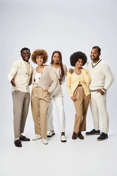 Groupe de jeunes hommes et femmes afro-américains posant les mains dans les poches sur fond gris — Photo de stock