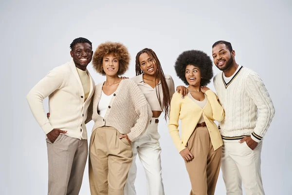 Groupe d'hommes et de femmes afro-américains heureux posant avec les mains dans les poches sur fond gris — Photo de stock