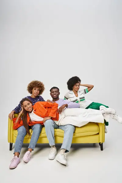 Feliz mulher afro-americana com dreadlocks deitado em voltas de amigos sentados no sofá amarelo — Fotografia de Stock