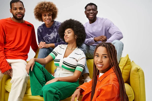 Happy african american women smiling near friends in bright casual wear on grey background — Stock Photo