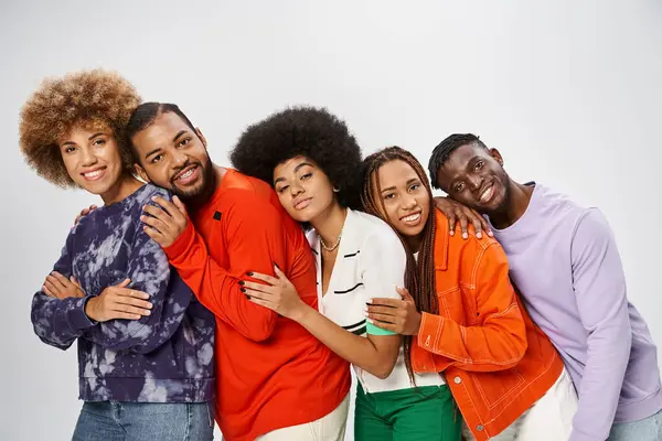 Heureuse communauté afro-américaine en tenue décontractée appuyée l'une sur l'autre sur fond gris, le 10 juin — Photo de stock