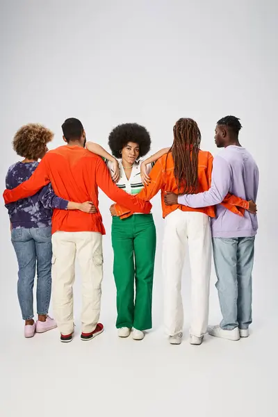 Curly african american woman leaning on friends hugging on grey background, Juneteenth concept — Stock Photo