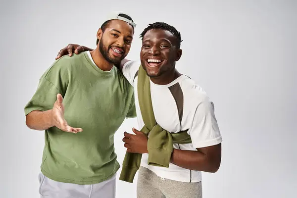 Smiling african american male friends in casual wear hugging on grey background, Juneteenth — Stock Photo