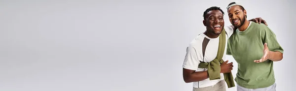Smiling african american male friends in casual wear hugging on grey background, Juneteenth banner — Stock Photo