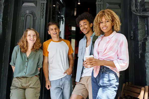 Heureux et branché étudiants multiethniques regardant la caméra près de l'auberge dans la rue urbaine, amitié — Photo de stock