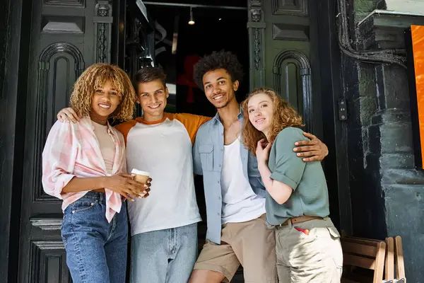 Group of joyful multicultural friends embracing and looking at camera near youth hostel in city — Stock Photo