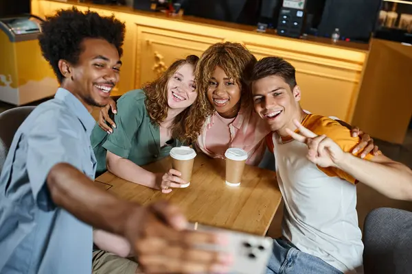 Heureux homme afro-américain prenant selfie avec des étudiants multiethniques à la mode dans le café de l'auberge, amitié — Photo de stock