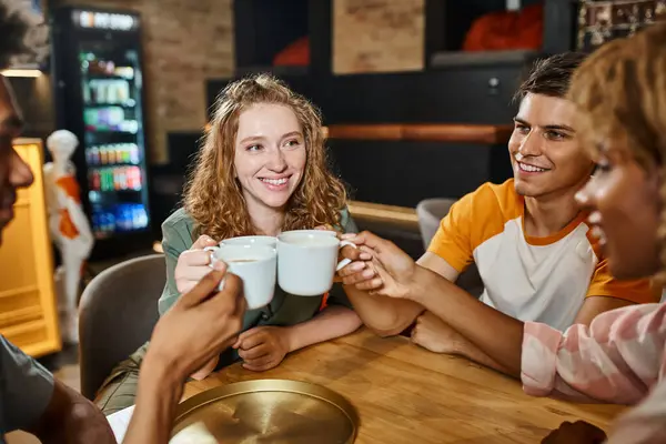 Pleased multiethnic buddies clinking coffee cups in lobby cafe of students hostel, friendship — Stock Photo