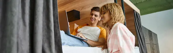 Smiling african american woman near friend networking on laptop on double-decker bed, banner — Stock Photo