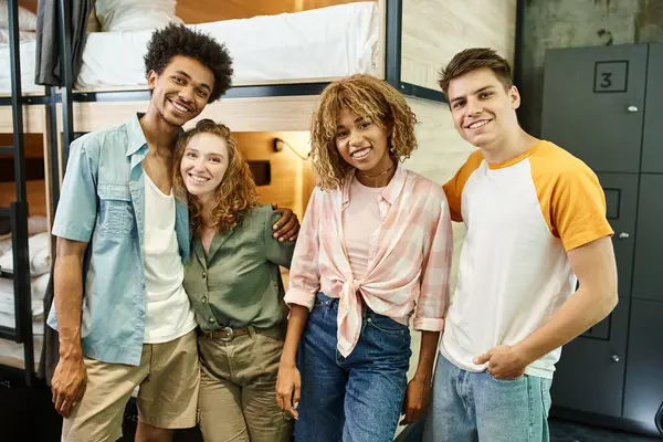 Étudiants multiethniques joyeux et élégant regardant la caméra dans la chambre de l'auberge moderne, amitié — Photo de stock