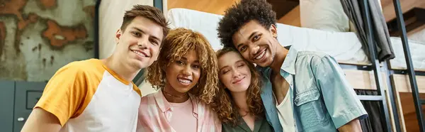 Diverse group of happy multiethnic students looking at camera in room of youth hostel, banner — Stock Photo