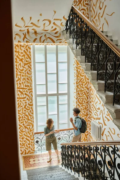 Young multiethnic couple walking on staircase with colorful walls in modern students hostel — Stock Photo