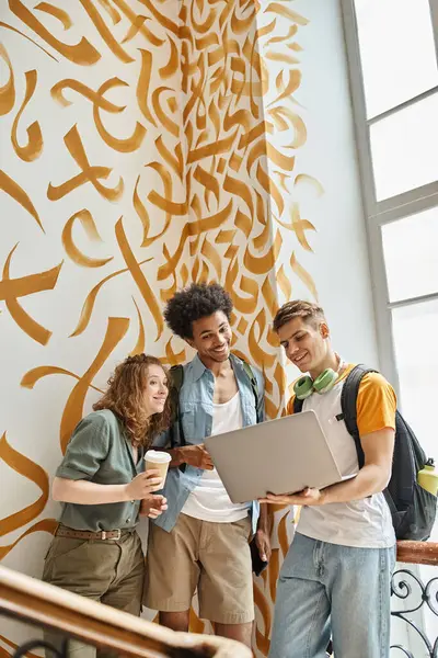 Excited multicultural students looking at laptop on staircase of hostel, friendship and travel — Stock Photo