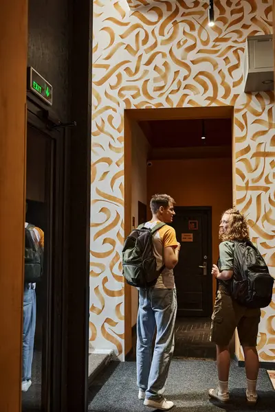 Back view of young couple of students with backpacks in corridor of hostel with modern design — Stock Photo
