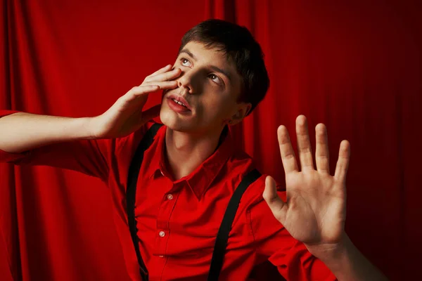 Suspense homem na camisa com suspensórios posando com as mãos levantadas no fundo vermelho, assustado — Fotografia de Stock