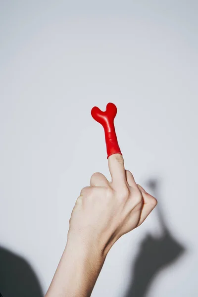Vista cortada de jovem provocante mostrando o dedo médio com balão vermelho no fundo cinza — Fotografia de Stock