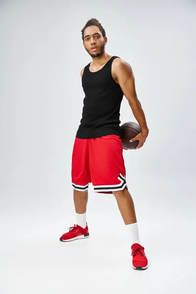 Good looking athletic african american man in sportwear posing with basketball and looking at camera — Stock Photo