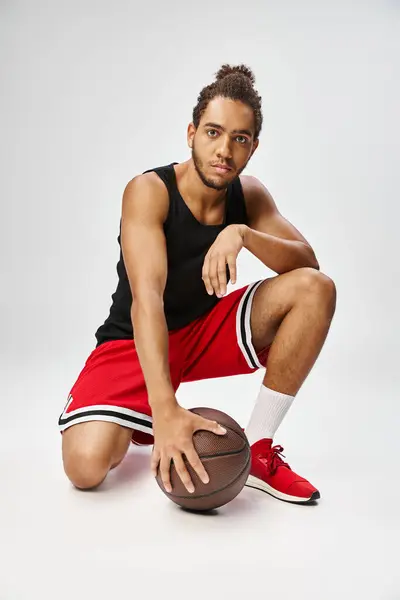 Good looking athletic african american sportsman posing with basketball and looking at camera — Stock Photo