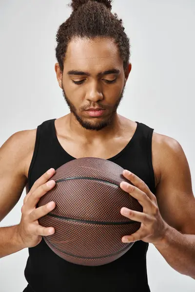 Appealing african american man in comfy uniform posing with his basketball in hands on gray backdrop — Stock Photo