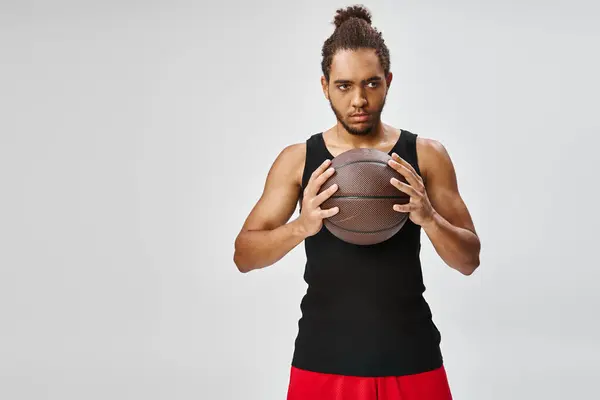 Appealing athletic african american man in sportwear holding basketball in hands and looking away — Stock Photo