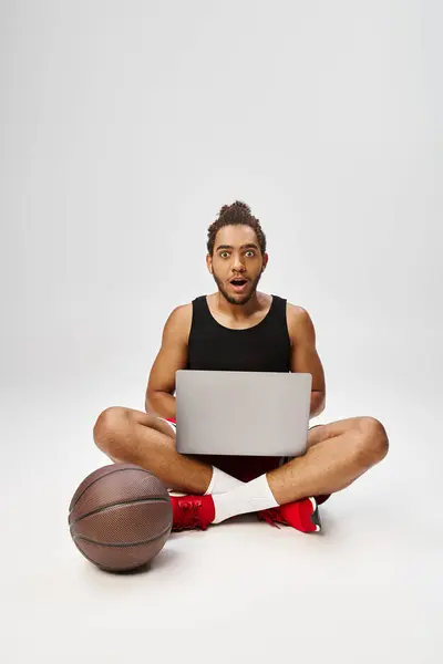 Schockierter afrikanisch-amerikanischer Mann in Sportbekleidung sitzt mit Laptop und schaut in die Kamera, Online-Wetten — Stockfoto