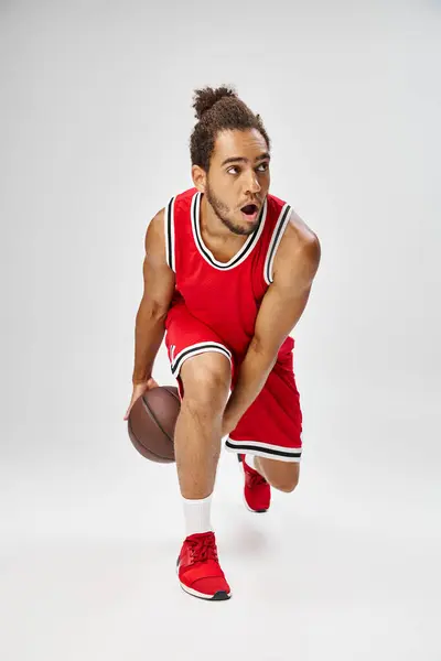 Handsome sporty african american man in vibrant uniform playing basketball on gray background — Stock Photo