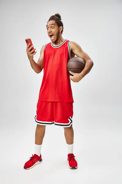 Sorpreso sportivo afroamericano in possesso di basket e guardando il telefono, scommesse online — Foto stock