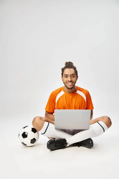 Joyous Africano americano desportista com futebol e laptop olhando para câmera, apostas on-line — Fotografia de Stock