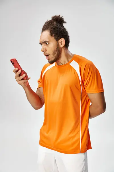 Scioccato sportivo afroamericano guardando il suo smartphone su sfondo grigio, scommesse online — Foto stock