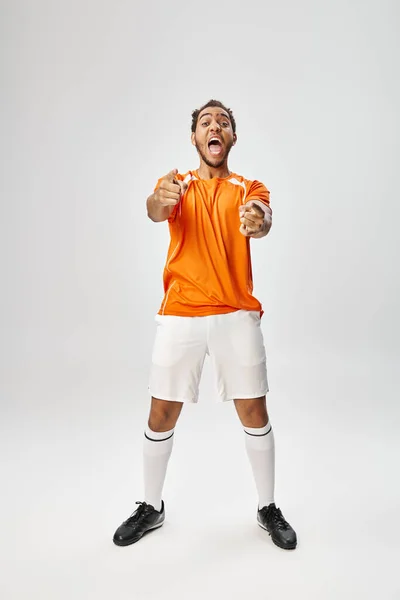 Cheerful athletic african american man in sportwear gesturing and pointing actively, online betting — Stock Photo