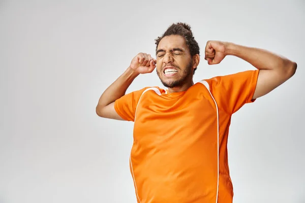 Handsome joyful african american man in comfy vivid sport uniform cheering on gray background — Stock Photo
