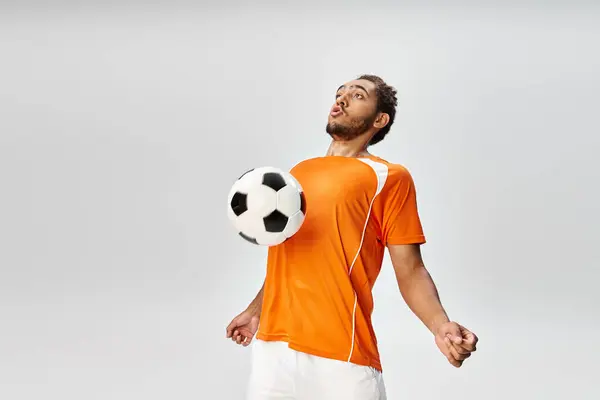 Appealing athletic african american man in sportwear playing football actively on gray background — Stock Photo