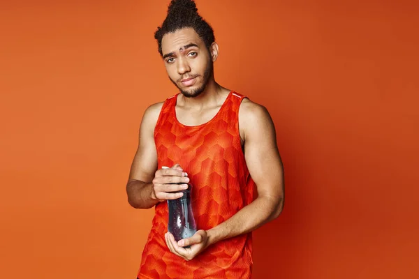 Homem americano africano atlético bonito no sportwear com garrafa de água que olha para a câmera — Fotografia de Stock