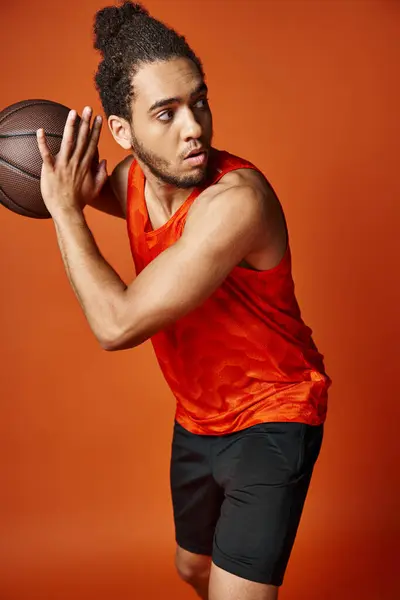 Good looking athletic african american man in sportwear playing basketball on orange background — Stock Photo