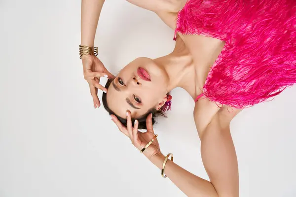 Upside down portrait of pretty brunette woman touching her forehead in fancy pink furry dress — Stock Photo