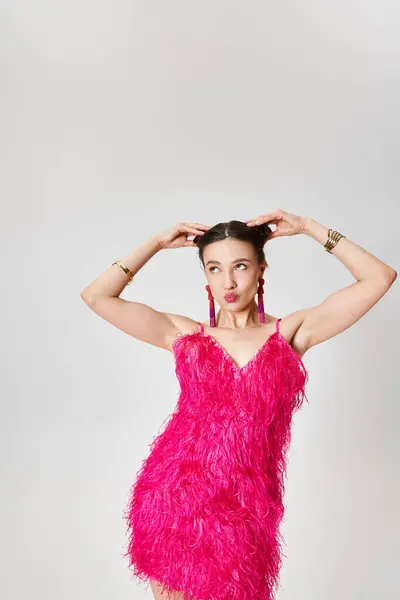 Зміст дівчини в модному рожевому платті, дивлячись з радості роблячи смішне обличчя і зворушливе волосся — стокове фото