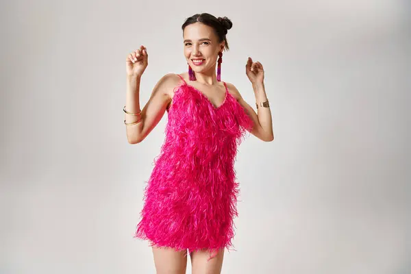 Jovem morena excitada em vigas de roupa rosa na moda, dançando em fundo cinza — Fotografia de Stock