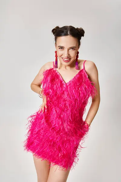 Казкова брюнетка в модному рожевому платті і вишукані прикраси сміються радісно ізольовані на сірому — стокове фото