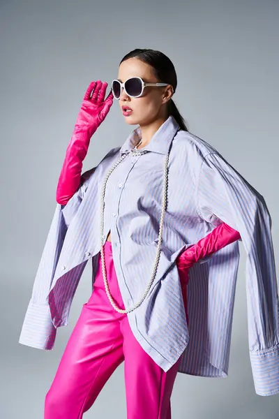 Confident brunette woman in pink leather pants and chic sunglasses stands elegantly — Stock Photo