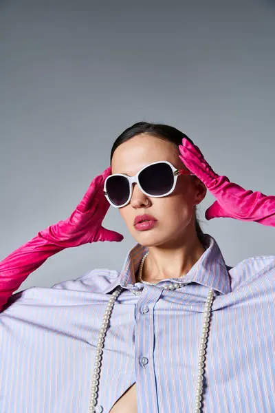 Модна брюнетка в рожевих рукавичках і модні сонцезахисні окуляри на сірому фоні — стокове фото