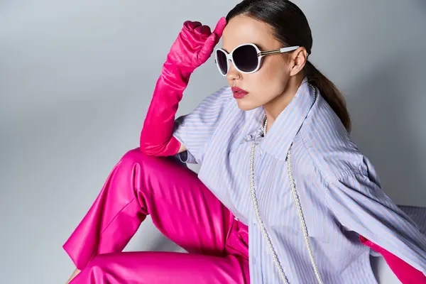 Attraktive Frau in violettem Hemd und Perlen, Sonnenbrille und rosa Handschuhe, die ihre Stirn berühren — Stockfoto