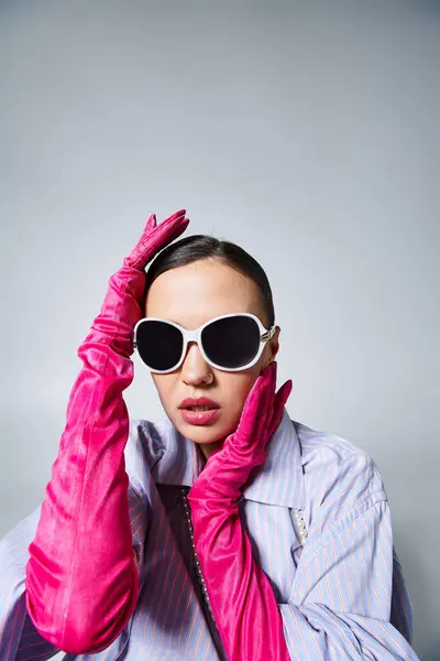Brünette Frau mit schicken rosa Handschuhen, die elegant ihr Gesicht berühren und Sonnenbrille und Perlen tragen — Stockfoto