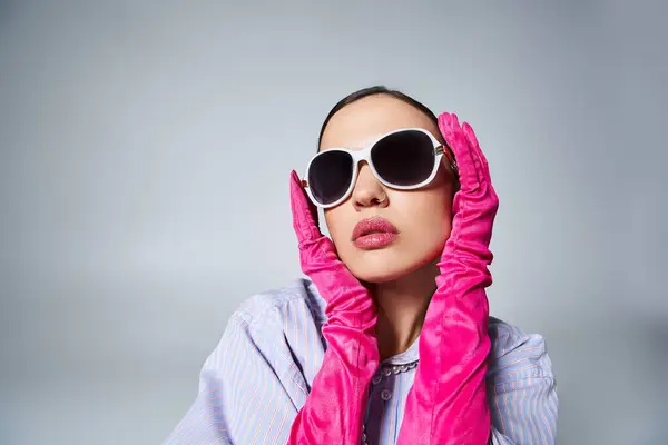 Привлекательная женщина в фиолетовой рубашке и жемчуге, в солнечных очках, нежно прикасаясь к лицу — стоковое фото