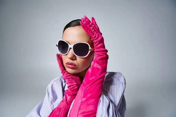 Strahlende Brünette in violettem Hemd und Perlen, trägt Sonnenbrille und berührt ihr Gesicht sanft — Stockfoto