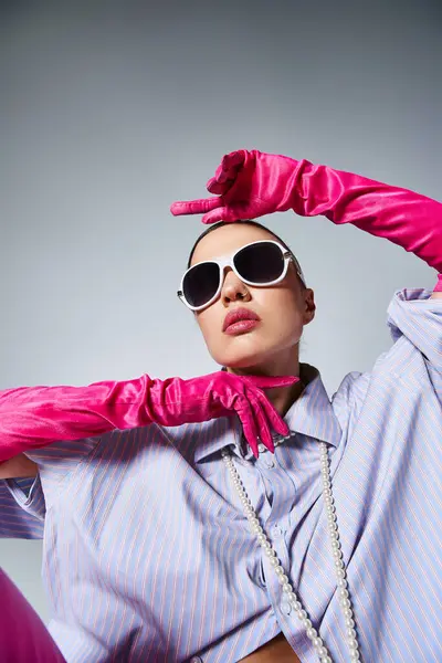 Brünettes Mädchen in violettem Hemd und Perlen, trägt Sonnenbrille, hält sanft die Hände vor dem Gesicht — Stockfoto